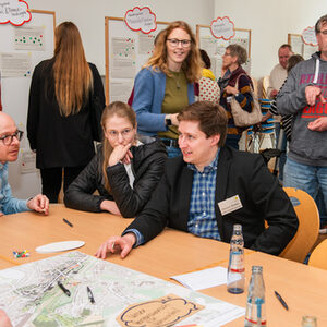 3 BürgerInnen unterhalten sich an einem Tisch